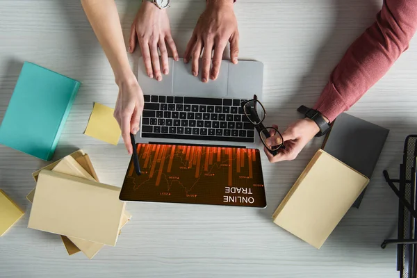 Cropped view of woman pointing at laptop with online trade website on screen near man holding glasses — Stock Photo