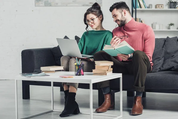 Весёлый мужчина смотрит на ноутбук рядом с женщиной в очках — стоковое фото