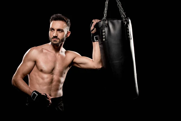 Muskulöser, gutaussehender Boxer, der in der Nähe eines Boxsackes steht, isoliert auf schwarz — Stockfoto