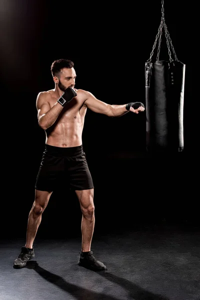 Bärtiger Boxer beim Training mit Boxsack auf schwarzem Hintergrund — Stockfoto