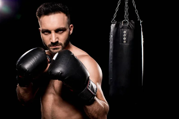Handsome sportsman wearing boxing gloves standing in boxing poseon black background — Stock Photo
