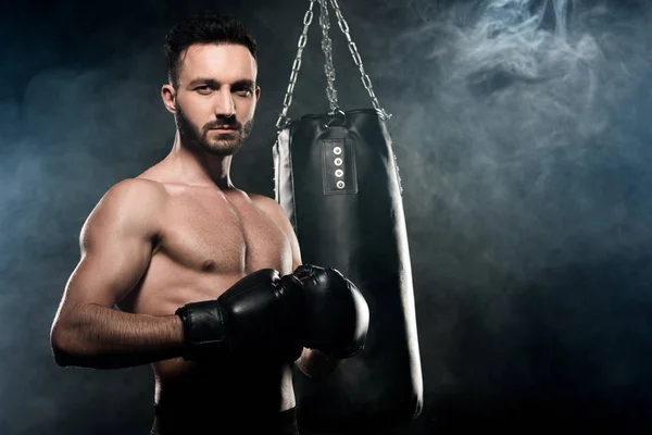 Handsome athlete standing in boxing pose on black with smoke — Stock Photo