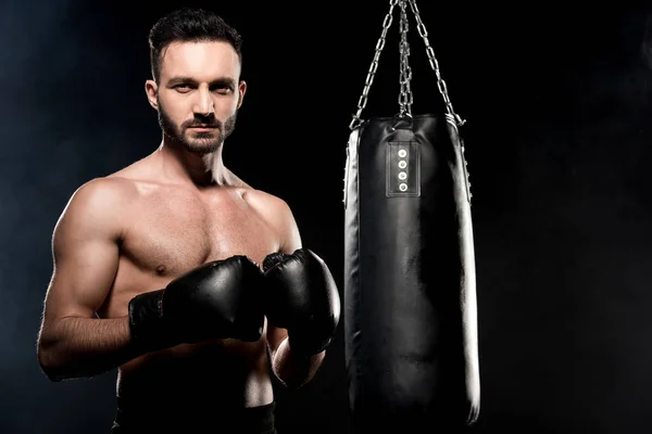 Красивый спортсмен в боксёрских перчатках, стоящий в боксёрской позе изолированный на черном — стоковое фото