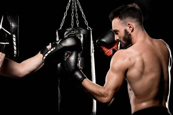 Handsome boxer fighting with man in punching gloves isolated on black — Stock Photo