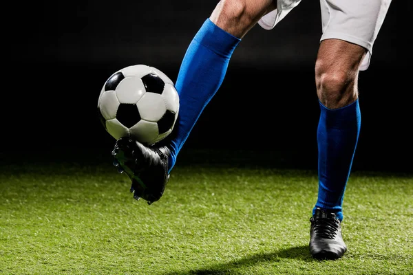 Vue recadrée du sportif jouant avec la balle sur l'herbe isolée sur noir — Photo de stock