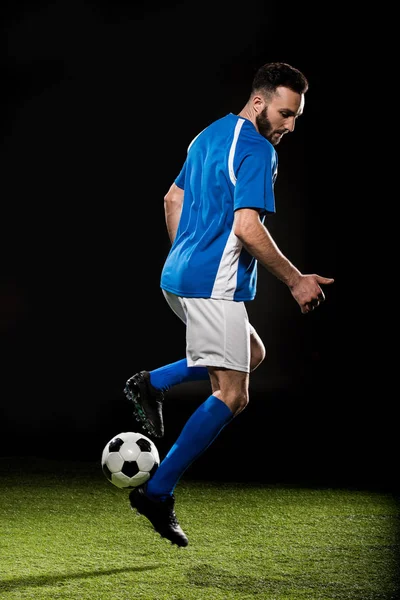 Desportista barbudo em uniforme jogando com bola isolada em preto — Fotografia de Stock