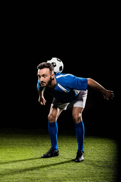 Sportif barbu en uniforme d'entraînement avec balle isolée sur noir — Photo de stock