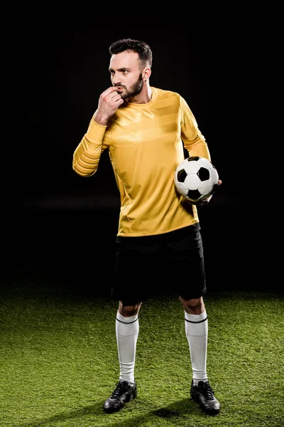 Bello barbuto allenatore soffiando fischio mentre tenendo palla isolato su nero — Stock Photo