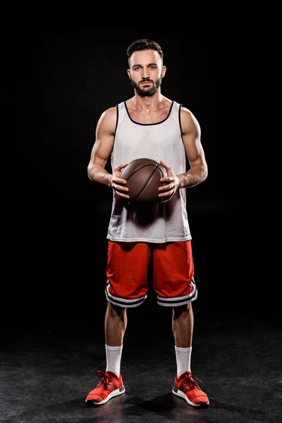 Schöner Sportler mit Ball in der Hand auf schwarzem Hintergrund — Stockfoto
