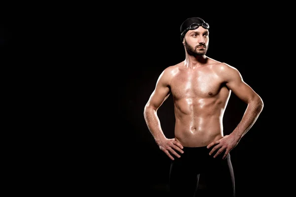 Nadador muscular de pie en gorra de natación y gafas de natación aisladas en negro - foto de stock