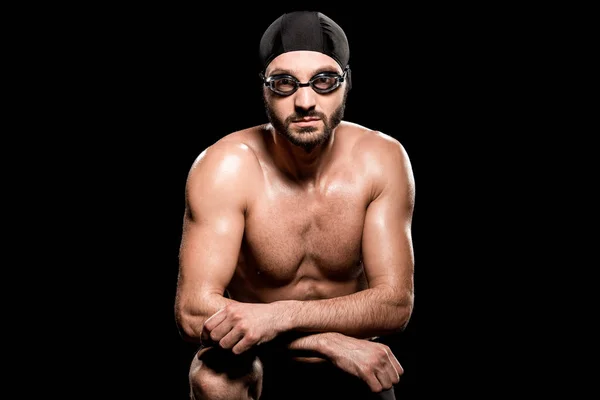 Beau nageur assis en bonnet de bain et des lunettes isolées sur noir — Photo de stock