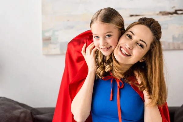 Smiling mother and kid in red cloaks looking at camera — Stock Photo