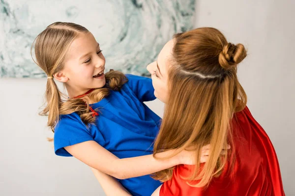 Lächelnde Mutter und Kind in roten Mänteln schauen einander an — Stockfoto