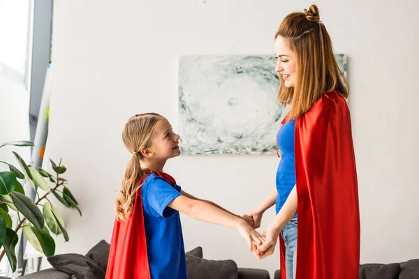 Madre y lindo niño en capas rojas sonriendo y mirándose entre sí - foto de stock