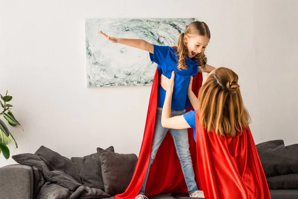 Mother and kid in red cloaks having fun at home — Stock Photo