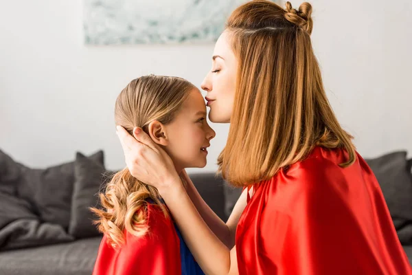 Schöne Mutter küsst süße Tochter zu Hause — Stockfoto