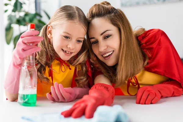 Мать и дочь в красных плащах и резиновых перчатках чистят дома — стоковое фото