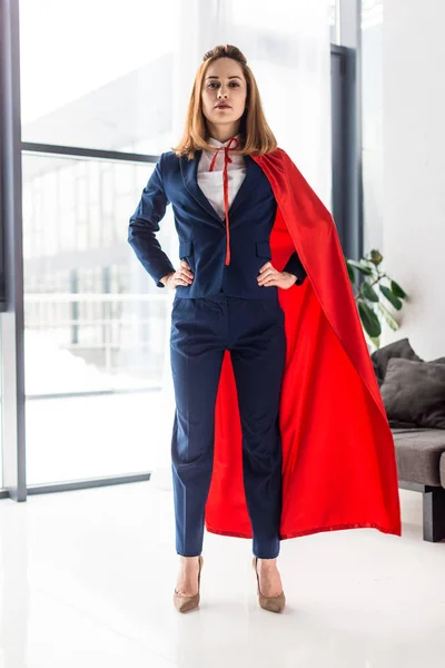 Mujer de negocios con confianza en traje azul y capa roja mirando a la cámara - foto de stock