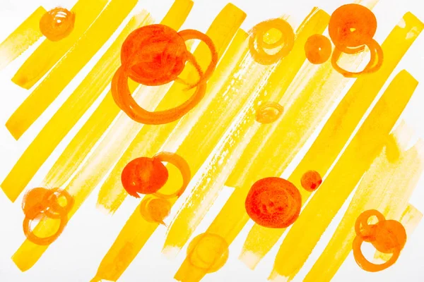 Vue du dessus des cercles orange et des coups de pinceau jaunes sur fond blanc — Photo de stock