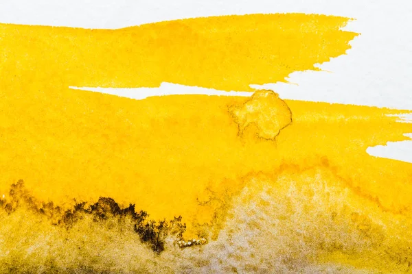 Vue de dessus du déversement d'aquarelle jaune sur papier blanc — Photo de stock