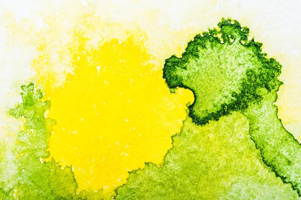 Вид сверху на желтый и зеленый акварели разливов на белом фоне — стоковое фото