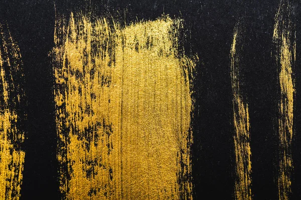 Top view of yellow watercolor brushstrokes on black paper — Stock Photo