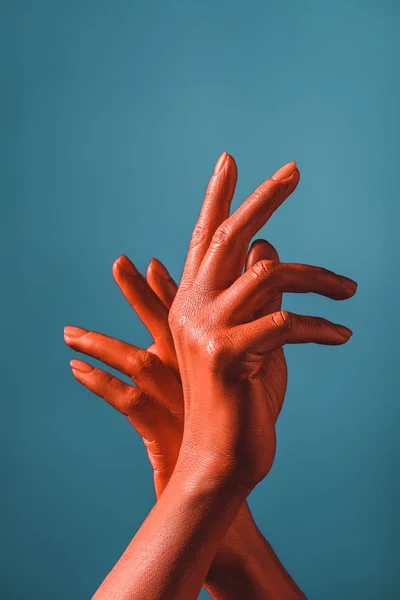 Partial view of woman gesturing with coral colored hands on blue background,  color of 2019 concept — Stock Photo