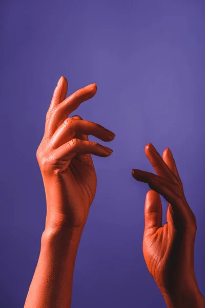 Vue recadrée des mains féminines de couleur corail sur fond violet, couleur du concept 2019 — Photo de stock