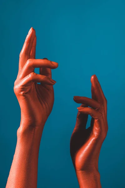 Cropped view of woman gesturing with coral colored hands on blue background, color of 2019 concept — Stock Photo