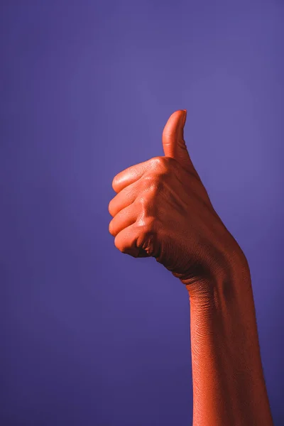 Partial view of woman showing thumb up on coral colored hand on violet background, color of 2019 concept — Stock Photo