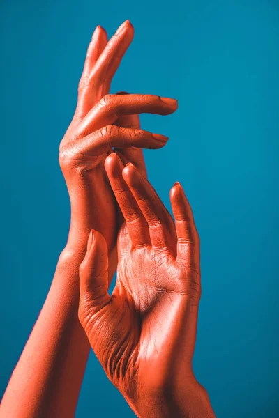 Vue recadrée des mains féminines de couleur corail sur fond bleu, couleur du concept 2019 — Photo de stock