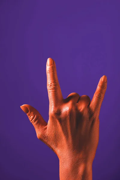 Vista parcial de la mujer que muestra el signo de roca por la mano de color coral sobre fondo violeta, el color del concepto 2019 - foto de stock