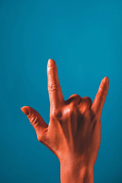 Vue recadrée de la femme montrant signe de roche par main de couleur corail sur fond bleu, couleur du concept 2019 — Photo de stock