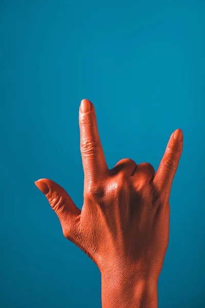 Vista recortada de la mujer que muestra el signo de roca por la mano de color coral sobre fondo azul, el color del concepto 2019 — Stock Photo