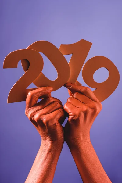 Vue partielle des mains féminines de couleur corail avec du papier découpé numéros 2019 sur fond bleu, couleur du concept 2019 — Photo de stock