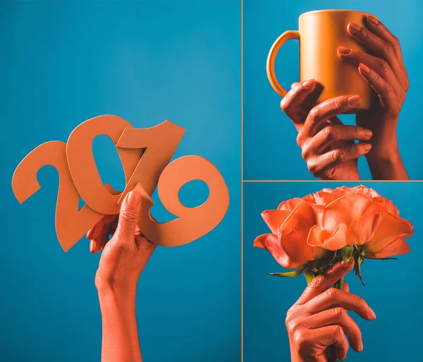 Vista parcial de las manos femeninas de color coral con números de papel de corte 2019 sobre fondo azul, concepto de color de 2019 — Stock Photo