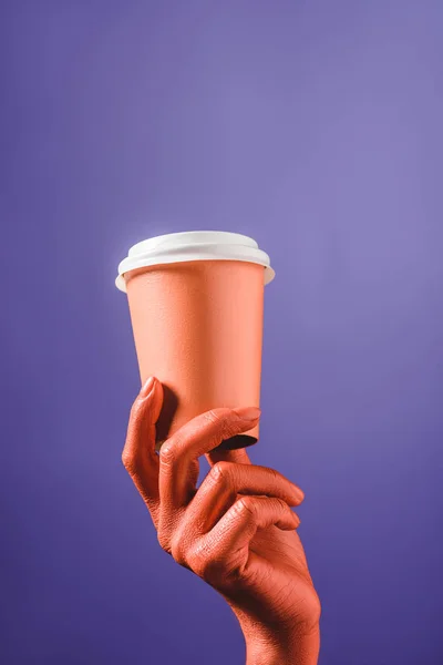 Vue recadrée de la main féminine de couleur corail avec tasse jetable corail sur fond violet, couleur du concept 2019 — Stock Photo