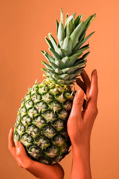 Vista recortada de las manos femeninas de color coral con piña sobre fondo de coral, concepto de color de 2019 - foto de stock