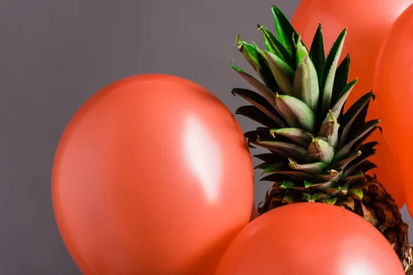 Coral air balloons and ripe pineapple fruit on grey background, color of 2019 concept — Stock Photo