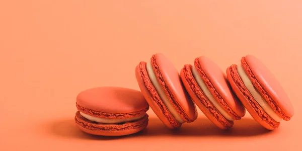 Tasty coral macarons on coral background, color of 2019 concept — Stock Photo