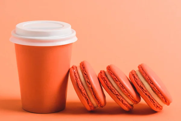 Köstliche Korallenmacarons und Pappbecher auf Korallenhintergrund, Konzept für 2019 — Stockfoto