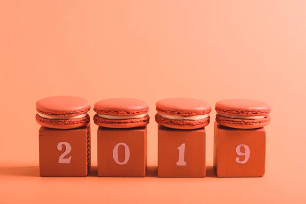 Cubos de coral com números 2019 e macarons em fundo de coral, cor do conceito 2019 — Fotografia de Stock