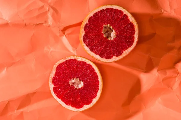 Grapefruithälften auf zerknülltem Papier strukturierte Korallenoberfläche, Farbe des Konzepts 2019 — Stockfoto