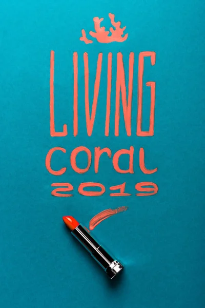 Color of year 2019 handwritten lettering with coral lipstick on blue background — Stock Photo