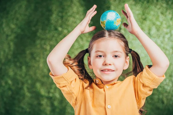 Adorable enfant tenant modèle globe sur la tête sur fond flou, concept jour de la terre — Photo de stock