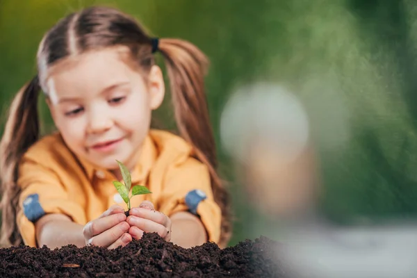 Messa a fuoco selettiva del bambino carino piantare giovane pianta su sfondo sfocato, concetto giorno terra — Foto stock