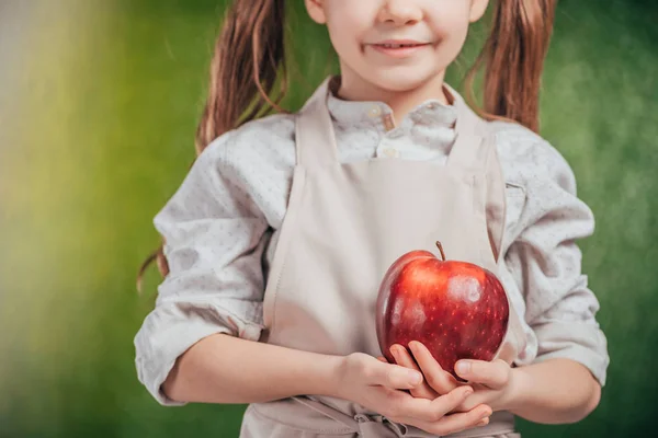 Обрезанный вид ребенка, держащего яблоко на размытом фоне, концепция Дня Земли — стоковое фото
