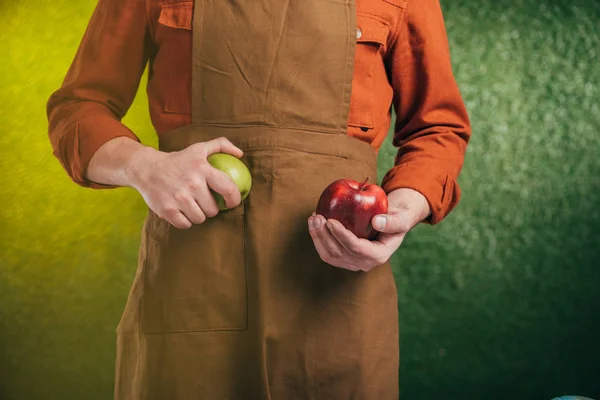 Vista parcial del hombre sosteniendo manzanas sobre fondo borroso, concepto del día de la tierra - foto de stock