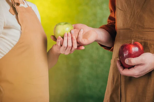 Vue partielle de l'homme et de la femme avec des pommes sur fond flou, concept de jour de la terre — Photo de stock