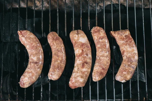 Vista dall'alto delle salsicce crude di maiale che cucinano sulle grigliate del barbecue — Foto stock